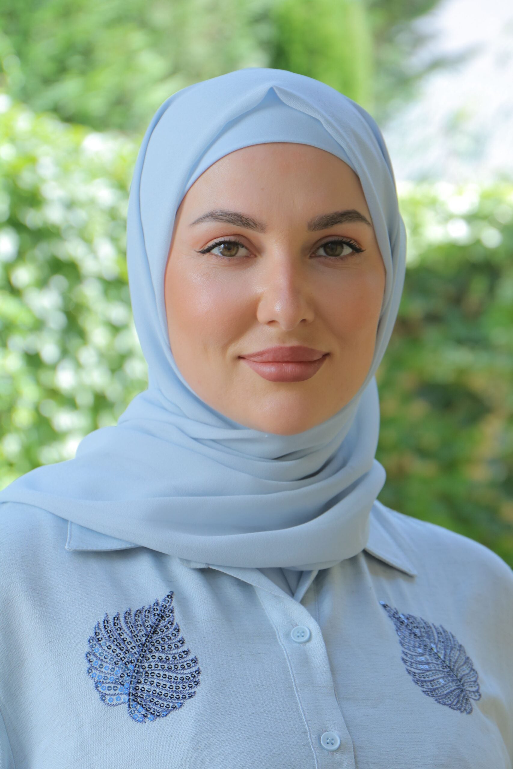 Model wearing a soft chiffon pastel blue hijab in a garden setting