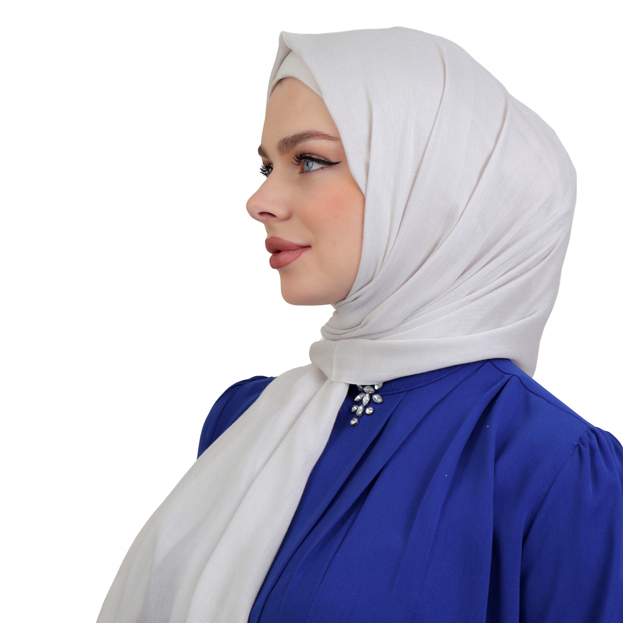 Close-up of a model wearing an off-white hijab styled with a royal blue blouse featuring pearl accents.
