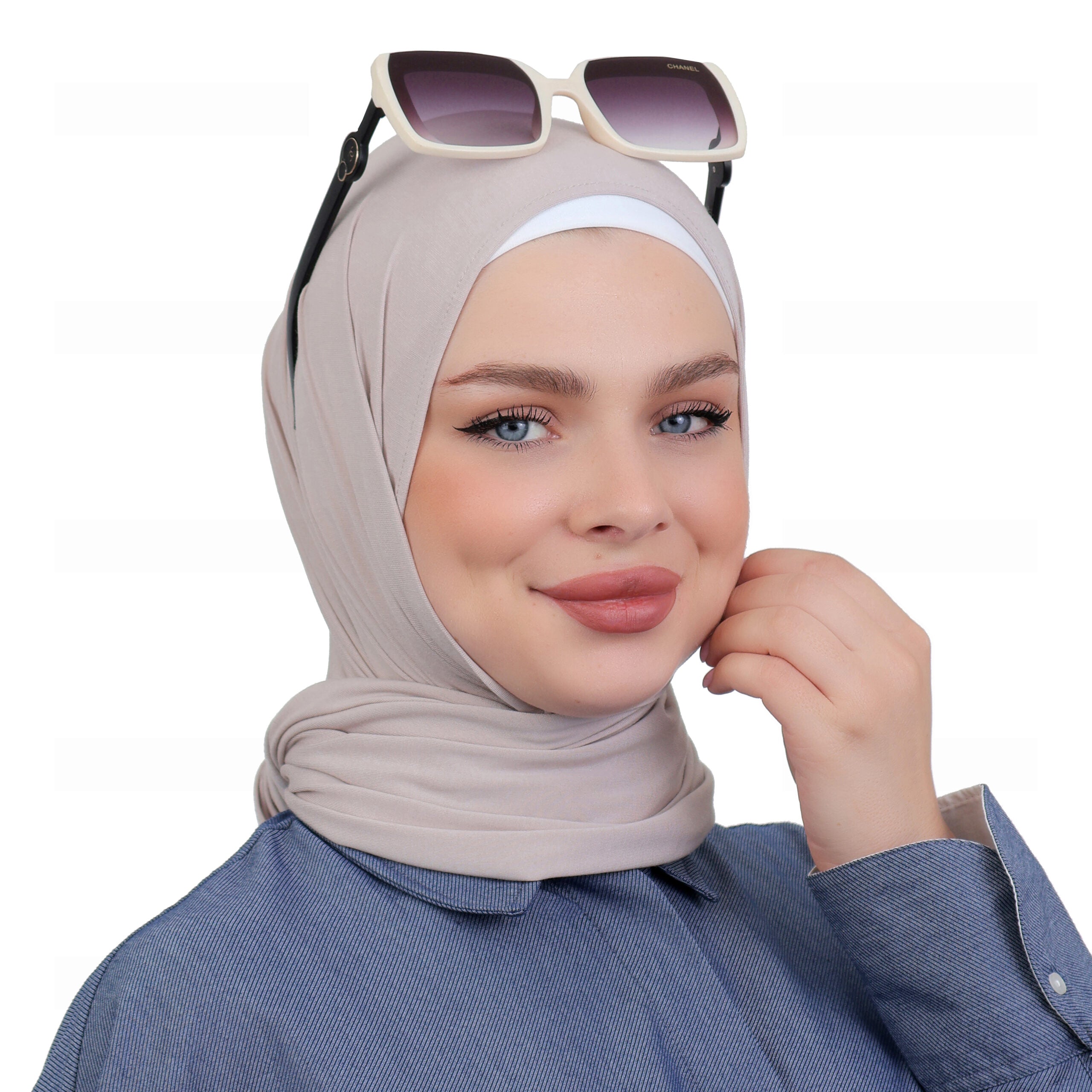 Close-up of a model wearing a beige triangle hijab layered over a white cap, paired with sunglasses for outdoor styling