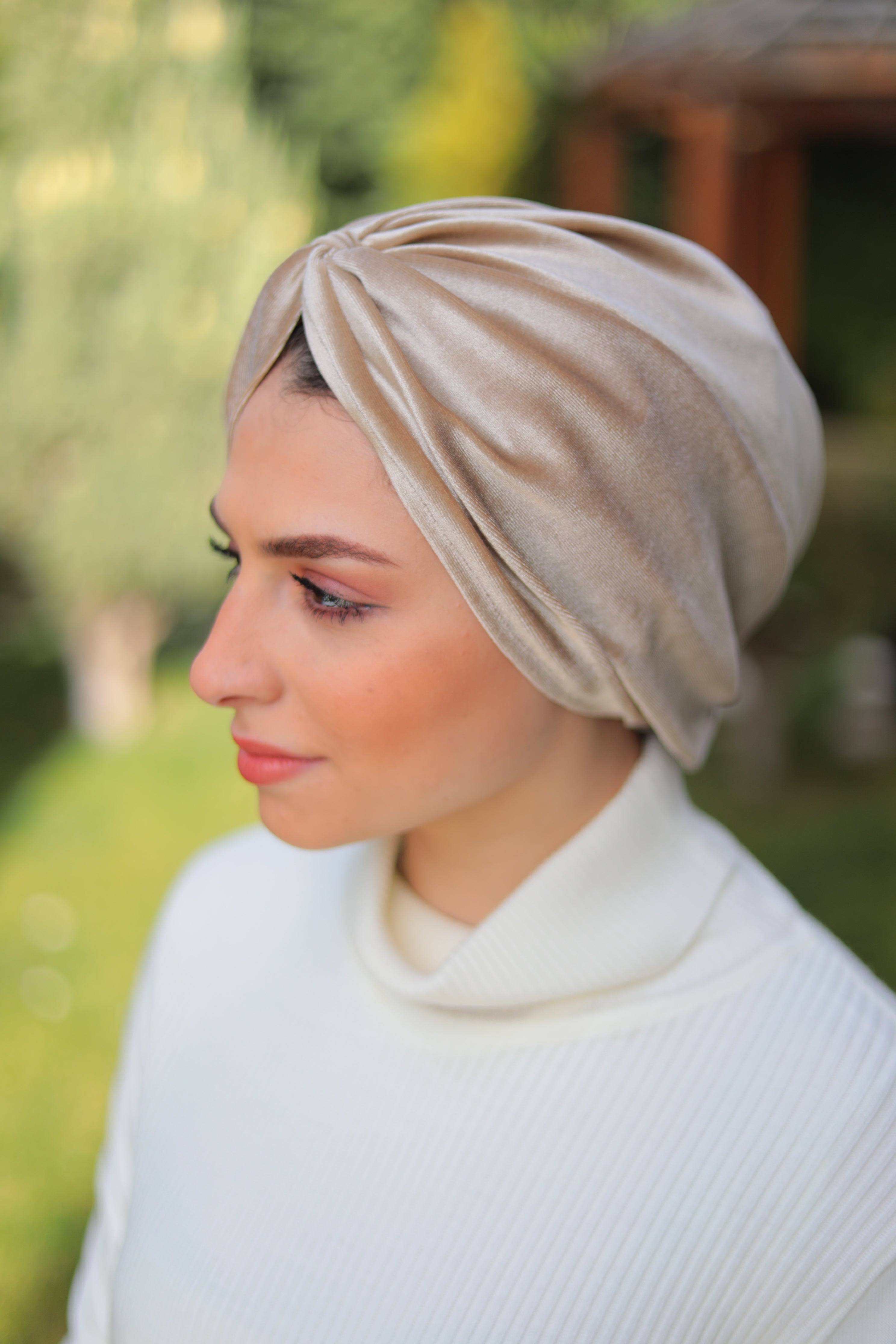 Outdoor image of a model wearing a satin beige turban, styled elegantly for formal and casual occasions