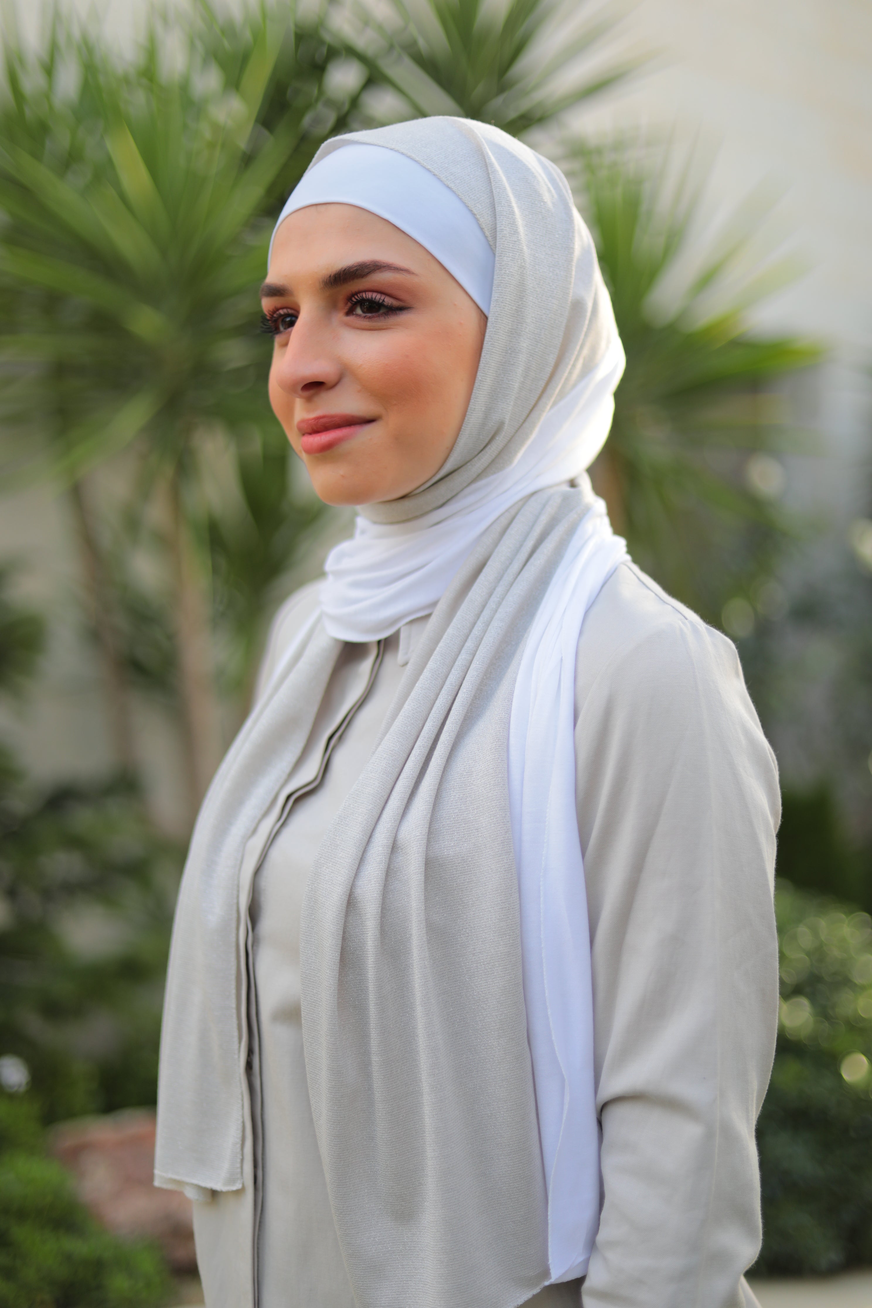Model wearing a white cotton and lame hijab, styled loosely with a minimalist beige outfit, perfect for formal wear