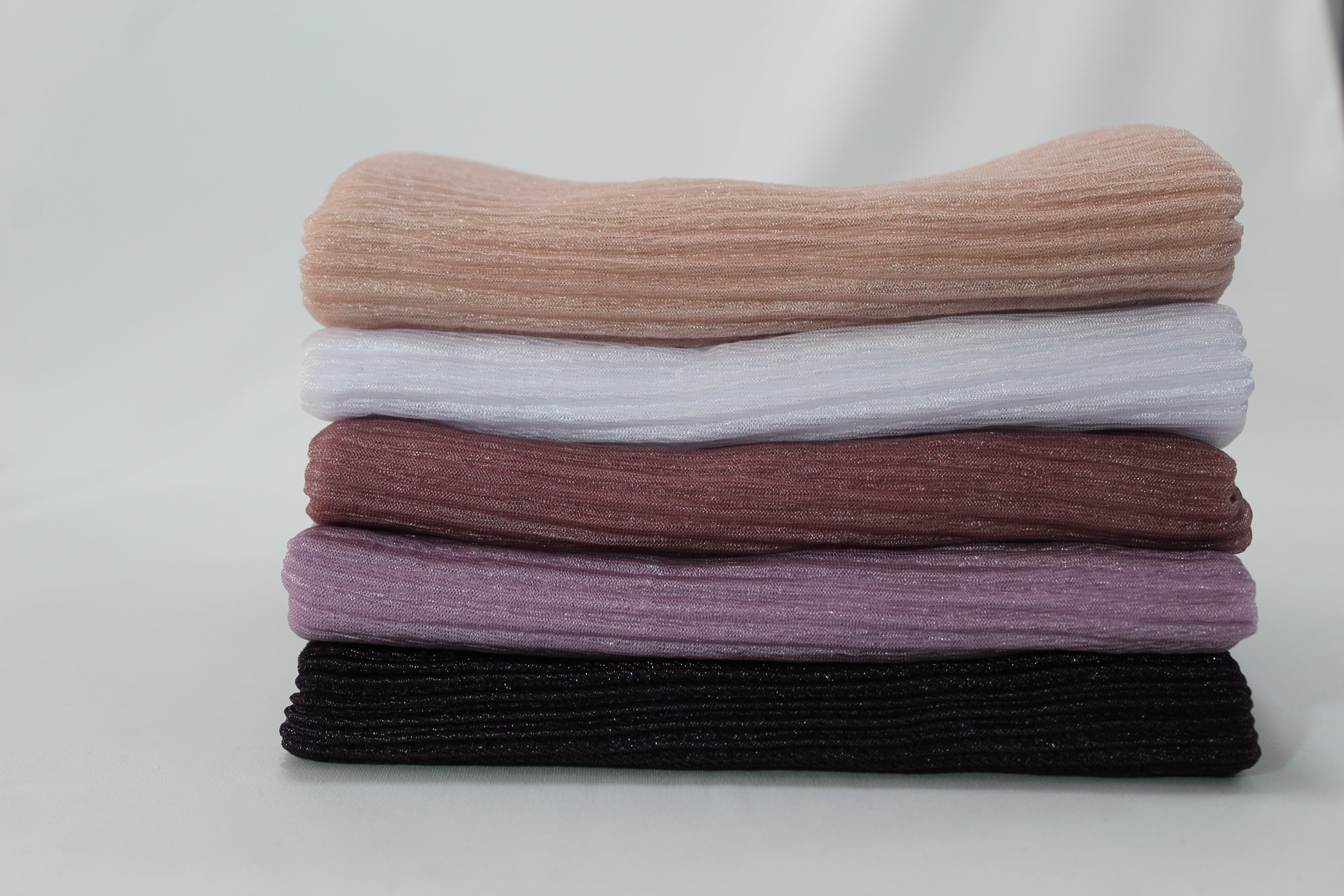 Stack of six premium ribbed hijabs in orange, white, burgundy, purple, and black. Perfect for versatile hijab styling options.