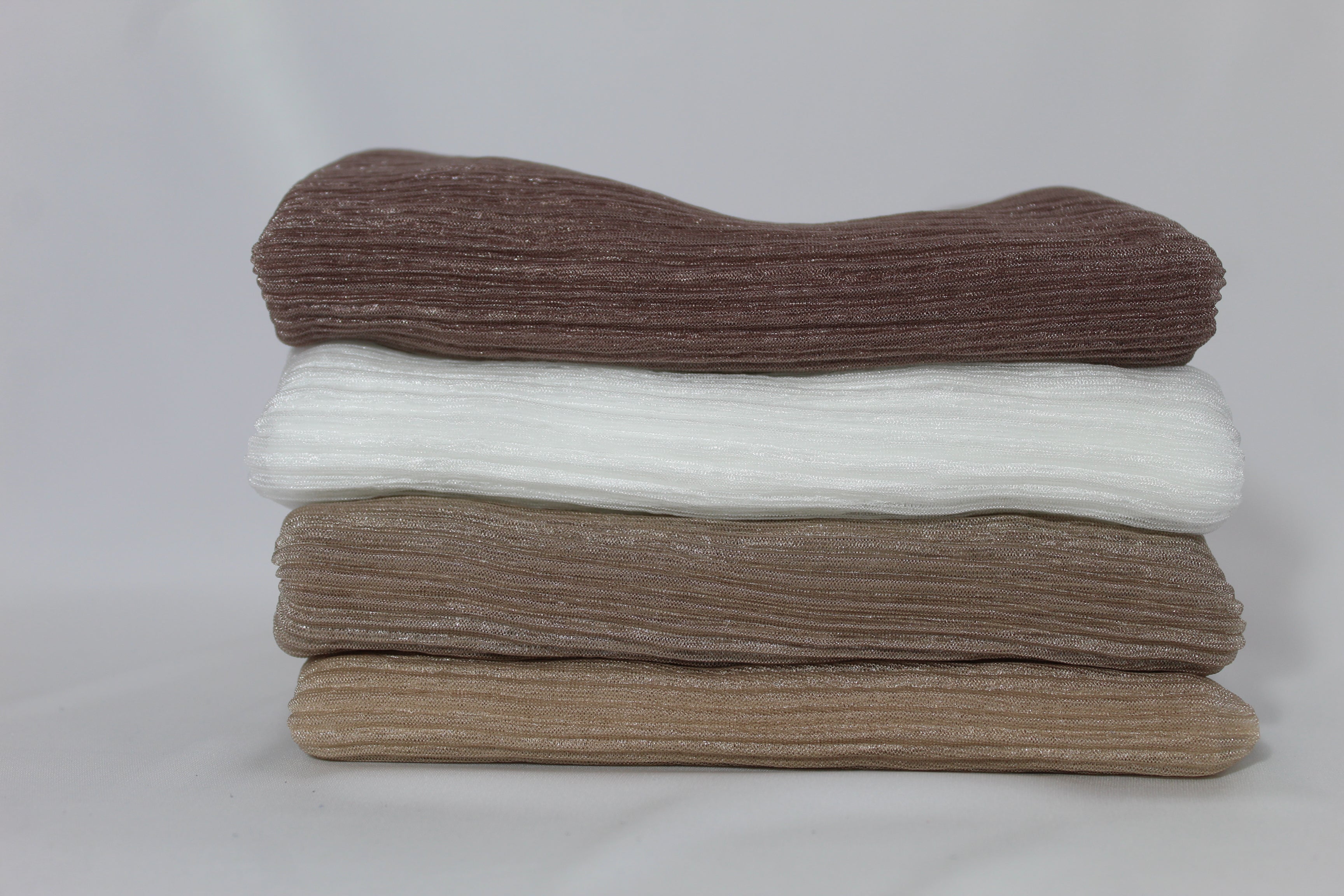 Five folded hijabs in soft browns and cream colors with ribbed texture. Elegant hijabs for modern modest fashion